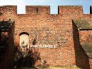 Fragment of the defensive walls of Toruń Old City adorned with dark bricks arranged in rhombic patterns and the plastered blind window